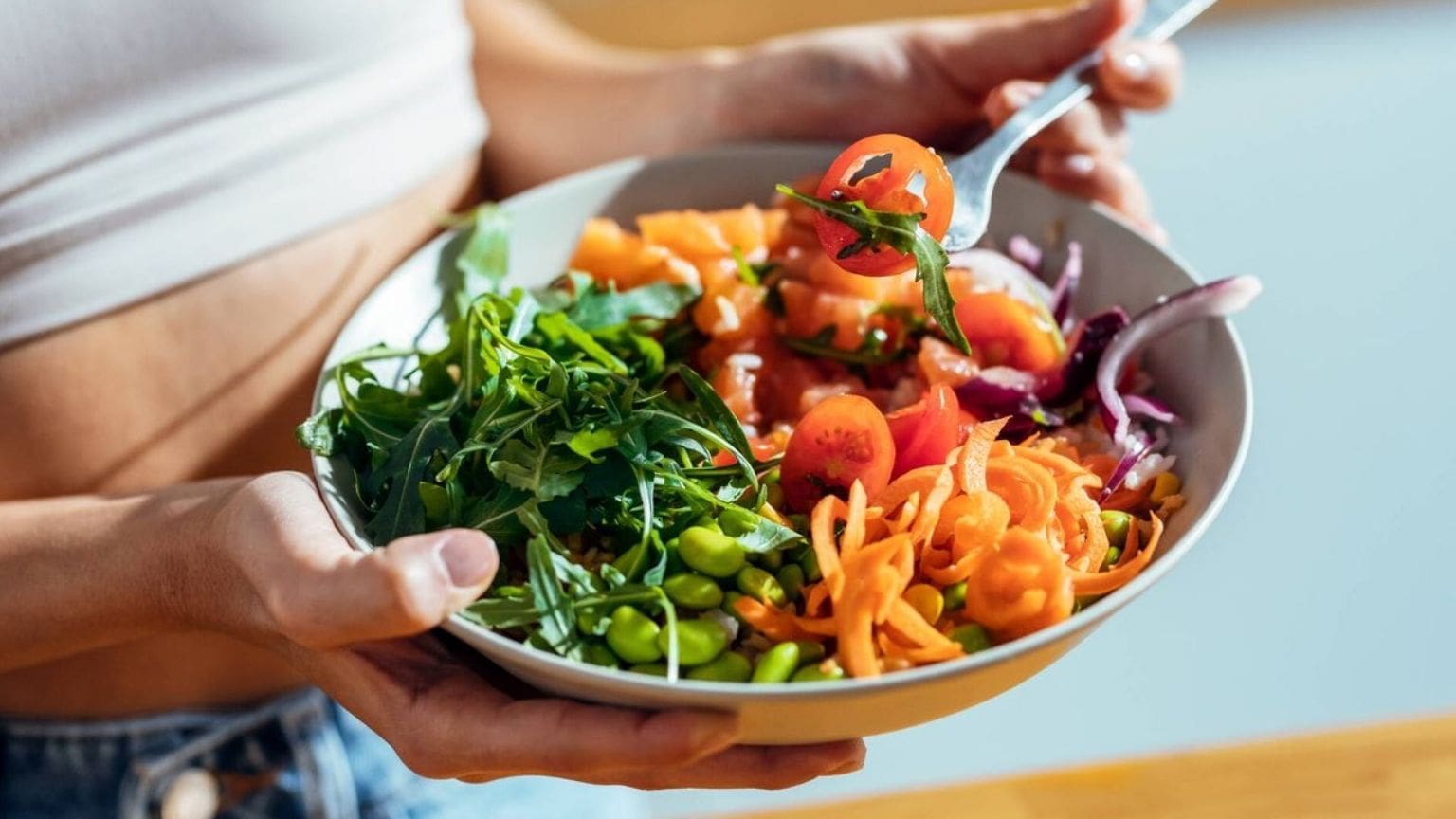 Mujer sosteniendo plato con comida saludable fitness en España