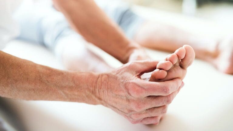 Fisioterapeuta aplicando un masaje de reflexología podal al pie de un paciente en España