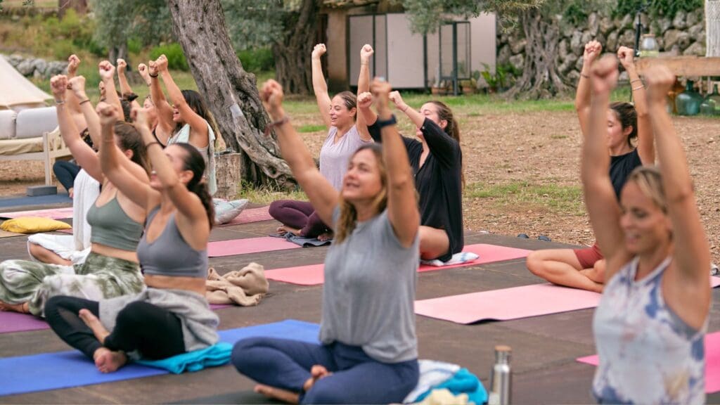 Personas practicando yoga al aire libre en un entorno natural, promoviendo bienestar físico y emocional.