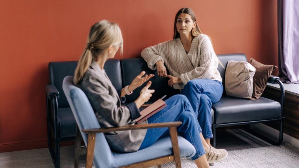 Sesión de psicoterapia en consulta. Psicólogo hablando con una paciente sobre salud mental.