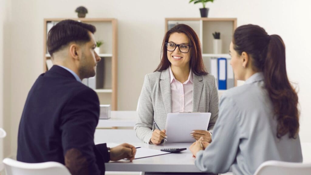 Corredor de seguros explicando las diferentes pólizas a un cliente en una reunión personalizada.