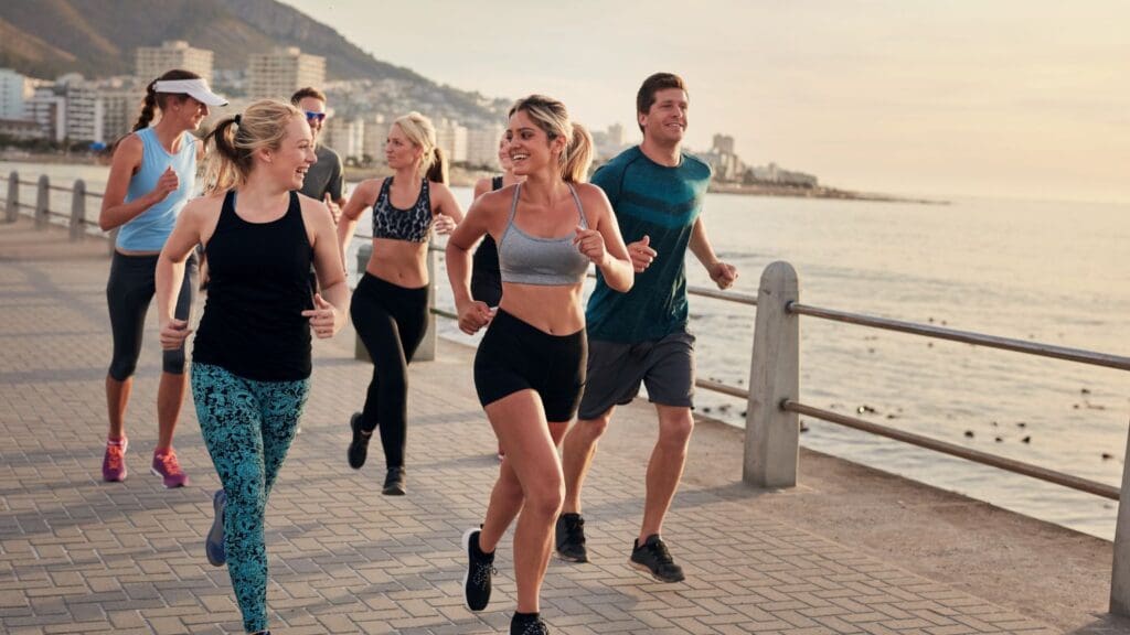 Personas haciendo ejercicio al aire libre en la playa de Barcelona, disfrutando de una sesión de fitness grupal con vistas al mar y un ambiente soleado.