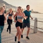 Personas haciendo ejercicio al aire libre en la playa de Barcelona, disfrutando de una sesión de fitness grupal con vistas al mar y un ambiente soleado.