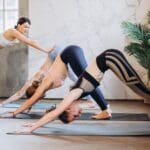 Personas practicando yoga en un estudio luminoso, guiados por un instructor experto. Clases de yoga para principiantes que promueven el bienestar físico y mental.