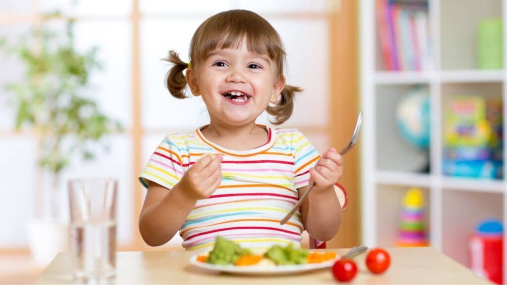 Niño disfrutando de una comida saludable con frutas y verduras para fomentar una buena nutrición.