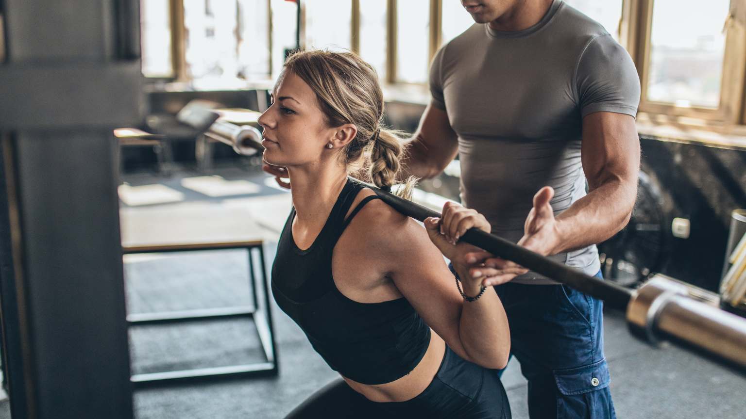 Entrenador deportivo dando consejos personalizados a un cliente en un gimnasio, ilustrando la importancia de elegir un instructor adecuado para mejorar el rendimiento físico.