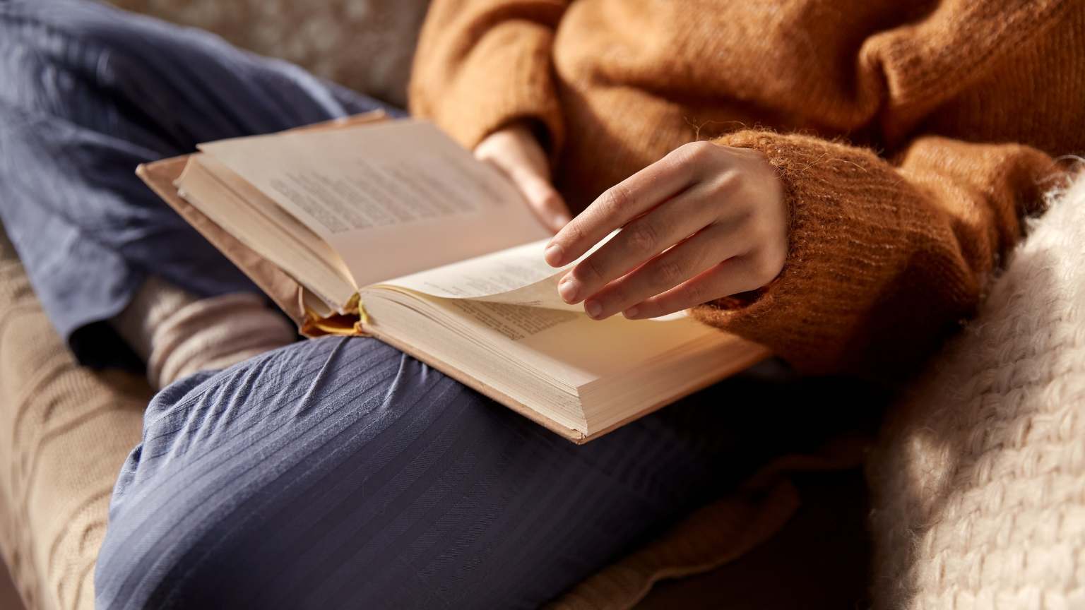 Persona leyendo un libro en un ambiente acogedor, rodeada de material de papelería y tomando notas. Representa los beneficios de la lectura y la organización personal.