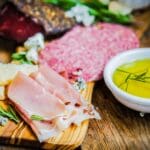 Tabla de embutidos y quesos gourmet con embutidos curados y quesos madurados, dispuesta sobre tabla rústica para compartir.