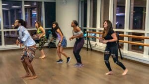 Grupo de personas practicando baile en un estudio profesional con espejos, demostrando técnica y pasión por la danza.