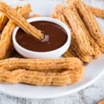 Churros tradicionales españoles servidos con chocolate caliente cremoso sobre una mesa rústica. Una delicia clásica que evoca sabor y tradición