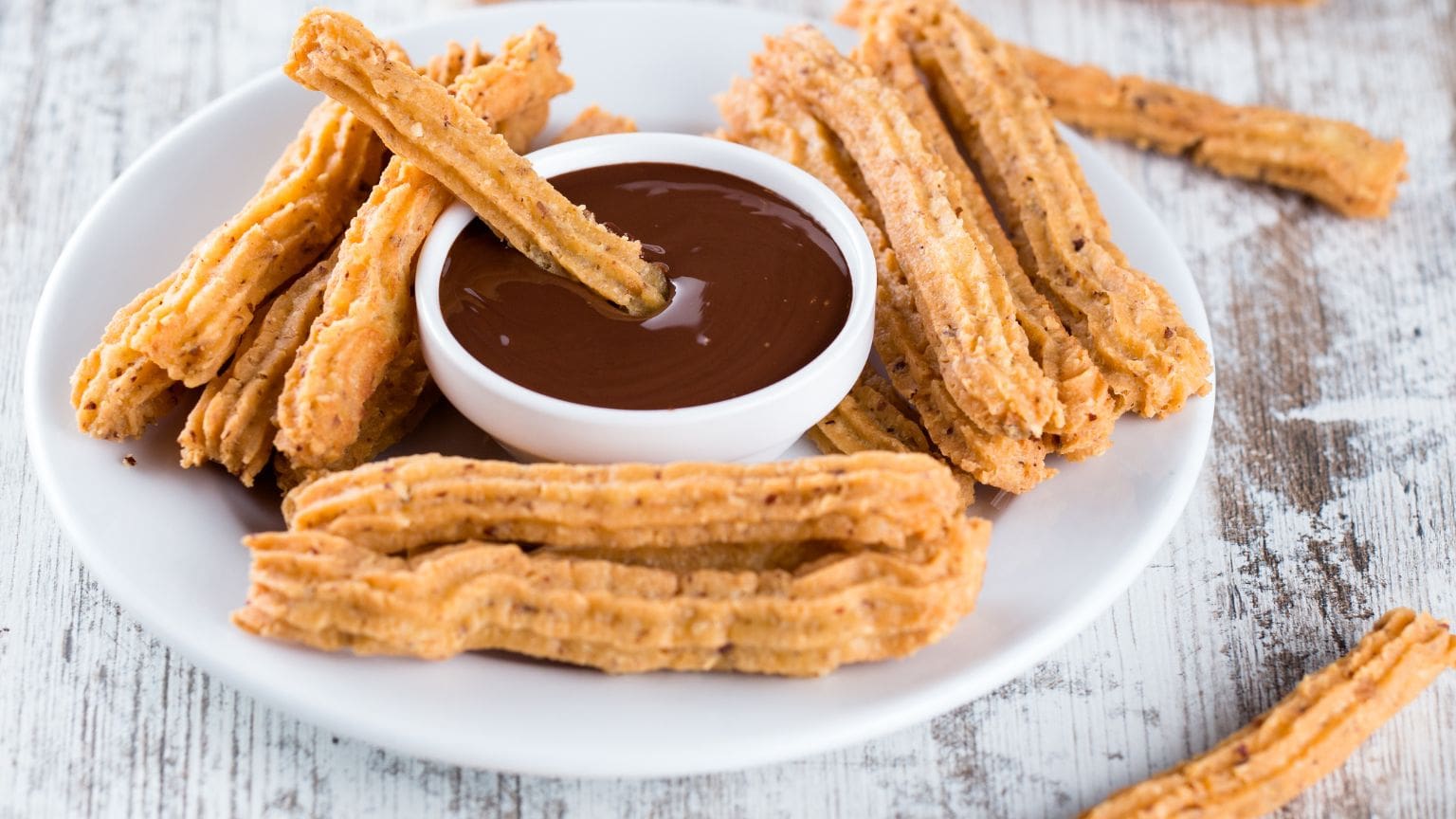 Churros tradicionales españoles servidos con chocolate caliente cremoso sobre una mesa rústica. Una delicia clásica que evoca sabor y tradición