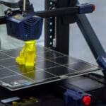 Impresión 3D en empresas. Ingeniero trabajando con impresora 3D para crear piezas y prototipos personalizados.