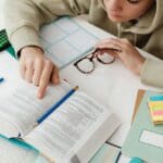 Estudiante concentrado utilizando técnicas de estudio efectivas con libros y portátil en un espacio organizado y acogedor, representando aprendizaje productivo.