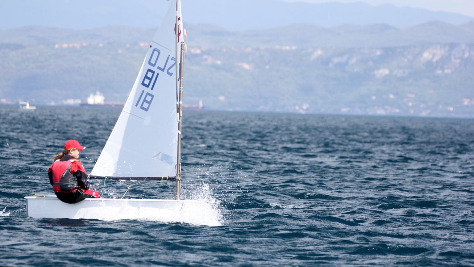 Persona navegando en un velero adaptado con tecnología inclusiva, disfrutando de la experiencia en el mar, con un enfoque en accesibilidad y autonomía.