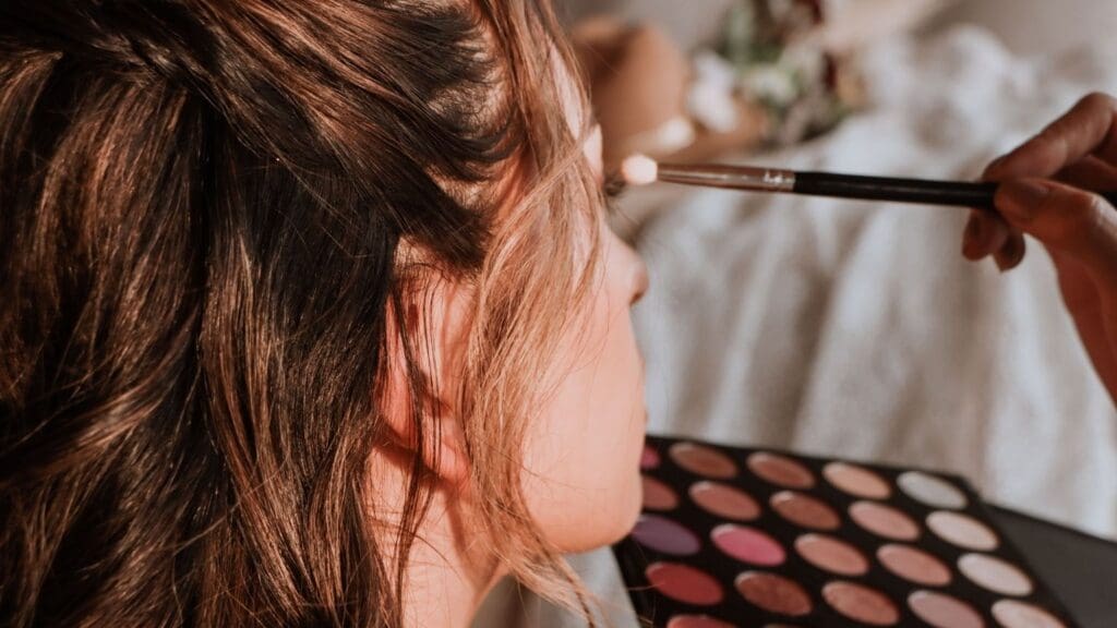 Mujer aprendiendo técnicas de automaquillaje en un taller con productos de maquillaje y herramientas profesionales