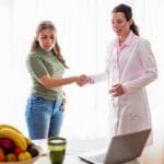 Persona preparando una comida saludable con frutas y verduras frescas, representando equilibrio y bienestar a través de la nutrición personalizada.