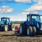 Máquina agrícola moderna cortando gavillas de ajo seco en un campo, destacando la mecanización y eficiencia en el sector agrícola.