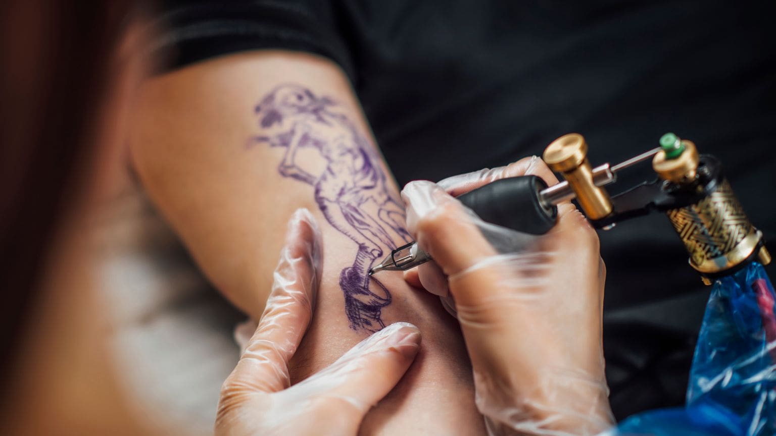 Professional tattoo artist creating a detailed forearm tattoo in a clean studio