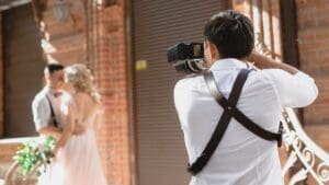 Fotógrafo profesional capturando un momento emotivo entre una pareja de recién casados durante su boda, con una iluminación cálida y natural.