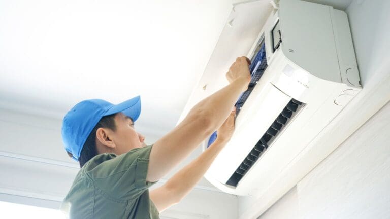 Técnico realizando el mantenimiento de un aire acondicionado en el hogar, asegurando un sistema de climatización eficiente y en óptimas condiciones.
