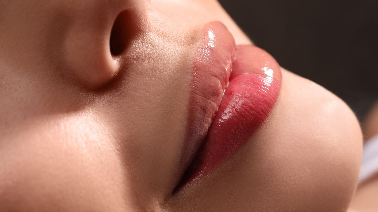 Primer plano de una mujer con labios definidos y color uniforme tras un tratamiento de micropigmentación en un centro de belleza.