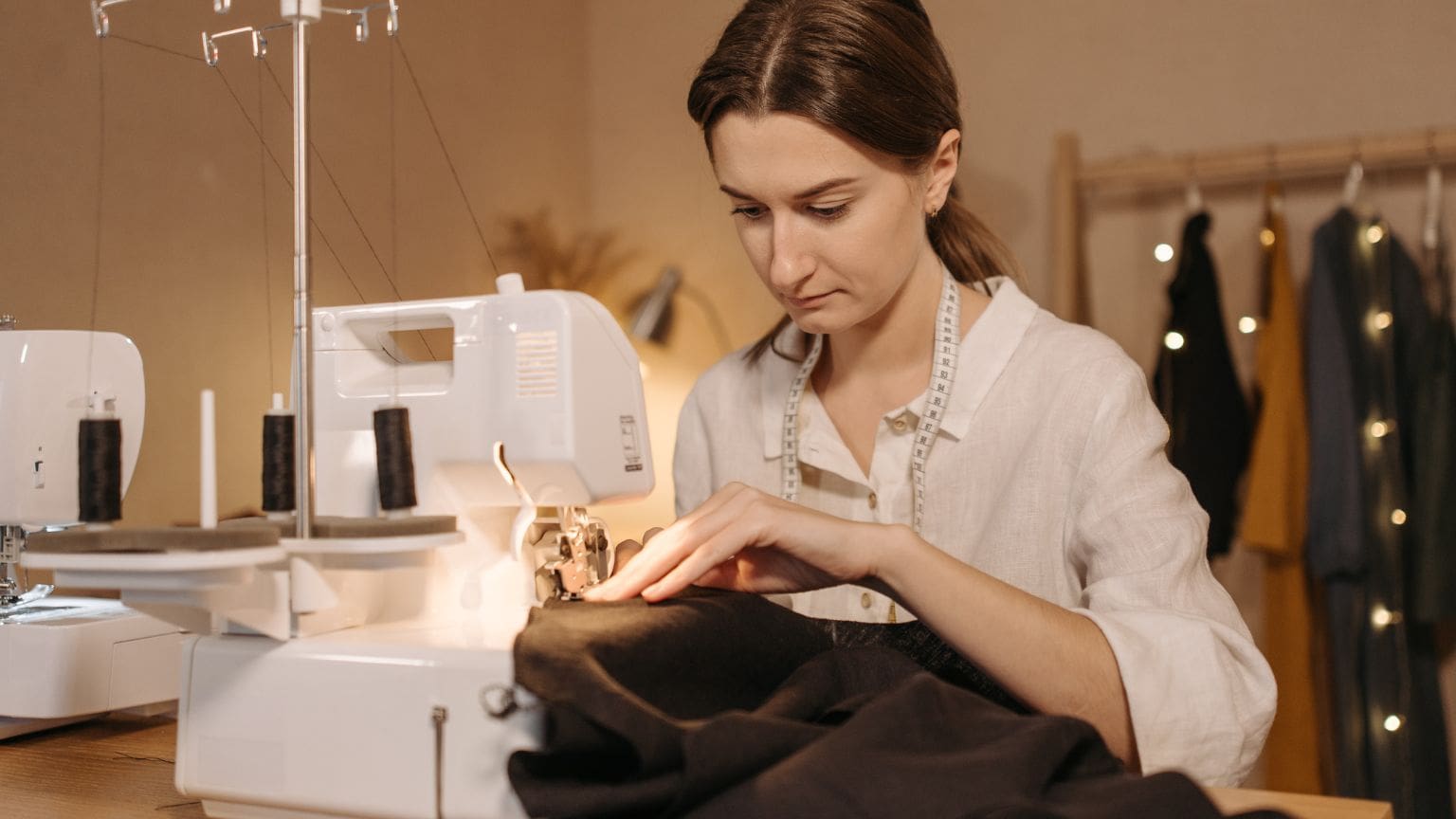 Mujer aprendiendo a coser en un taller con máquina de coser y herramientas básicas, ideal para principiantes en costura y confección.