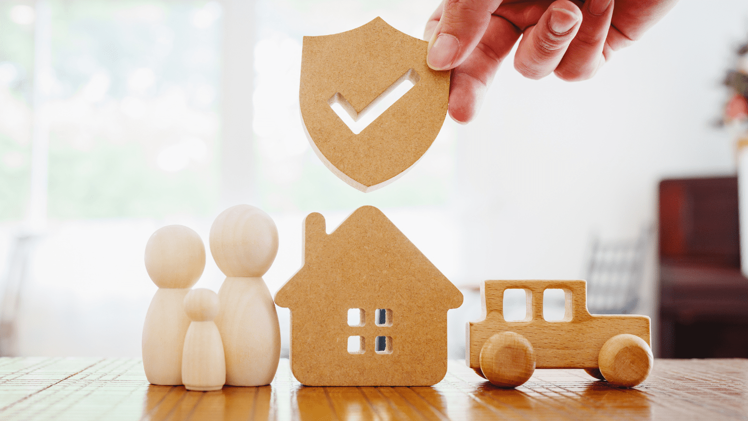 Representación de una familia, una casa y un coche, junto a un símbolo de seguro, ilustrando protección y seguridad financiera.