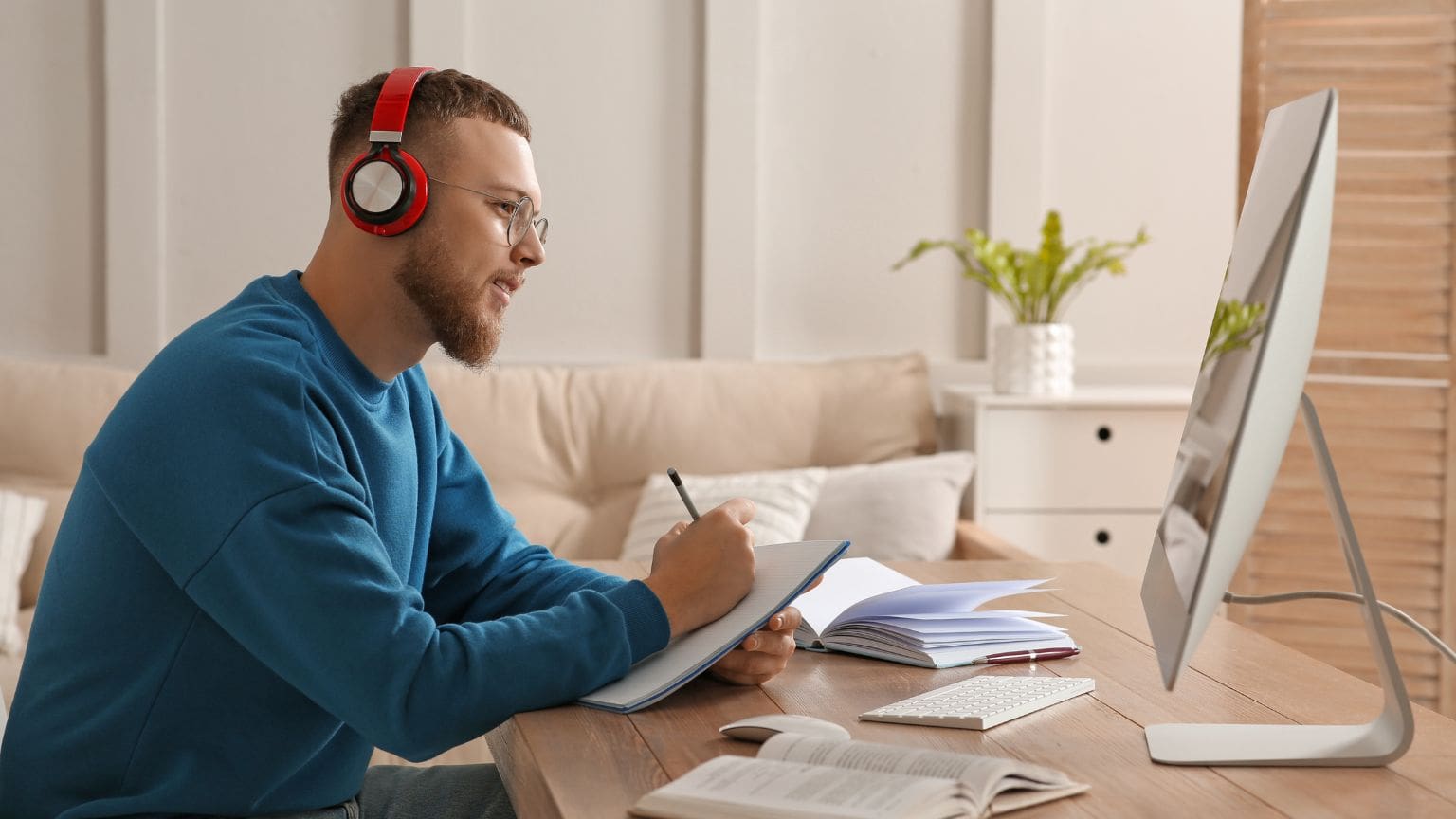 Persona estudiando un curso de psicología online desde casa con un ordenador y apuntes, representando la formación flexible y accesible en psicología