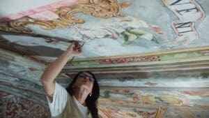 Artista pintando un mural decorativo en una pared, aplicando técnicas de pintura mural para transformar el espacio con arte y color.
