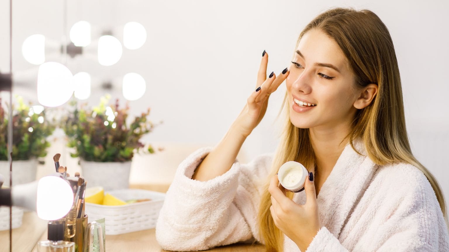 Mujer aplicando productos de belleza en su rutina diaria, con skincare y maquillaje esencial sobre una mesa elegante.