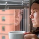 Mujer reflexiva sentada en silencio, representando ansiedad silenciosa y carga emocional interior.