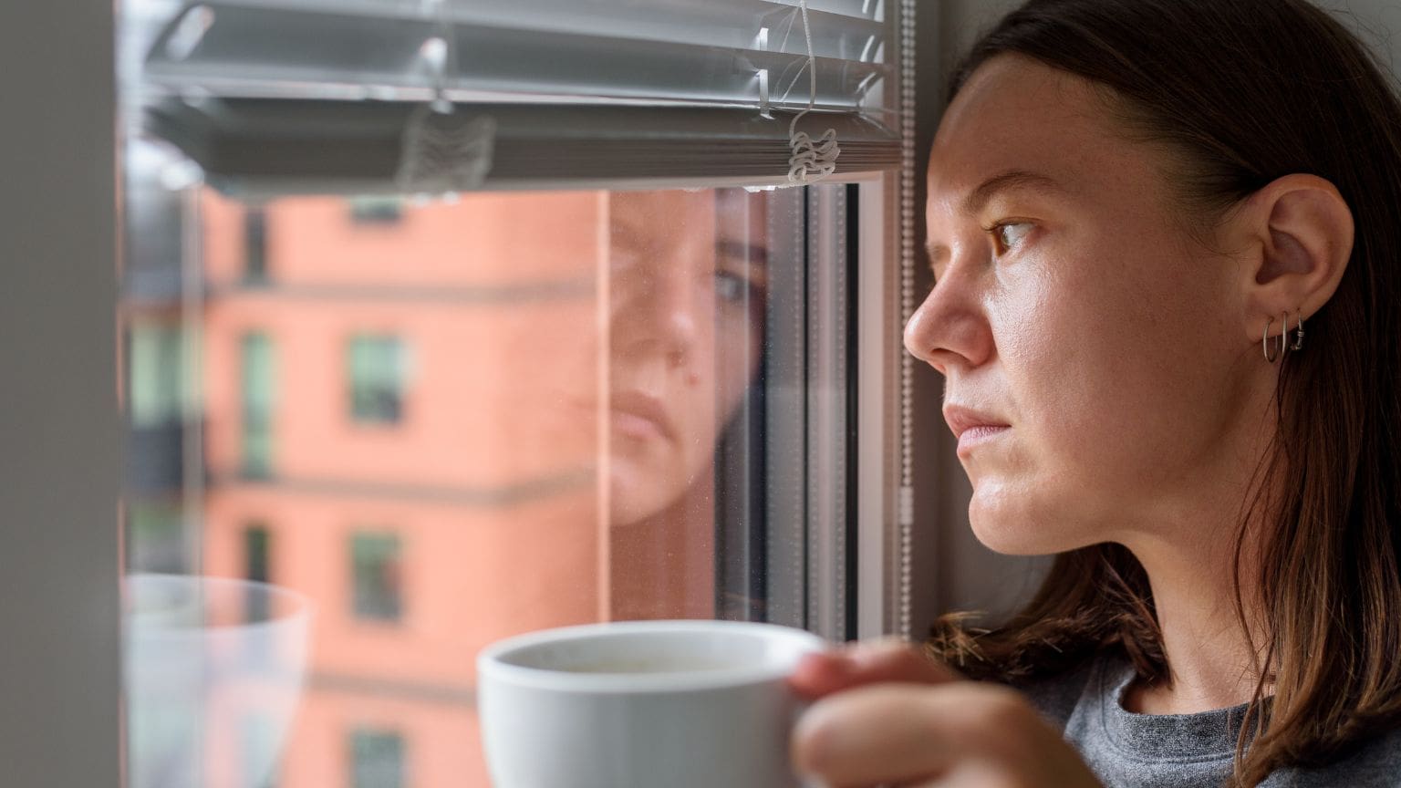 Mujer reflexiva sentada en silencio, representando ansiedad silenciosa y carga emocional interior.
