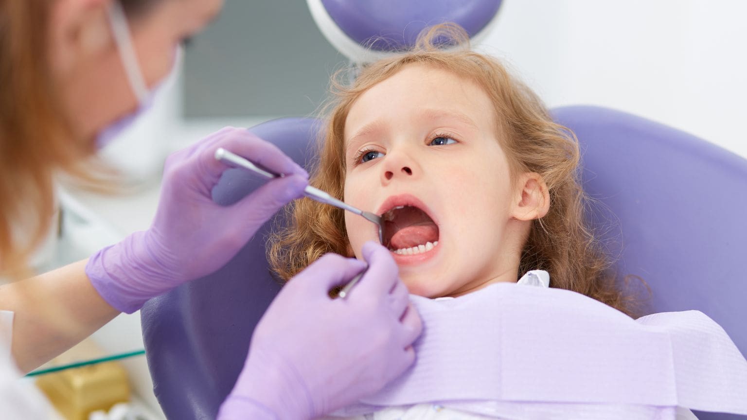 Niño recibiendo tratamiento dental en camilla pediátrica con equipamiento especializado y ambiente adaptado