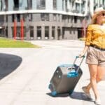 Mujer caminando con maleta después de elegir outfits de primavera para viaje.