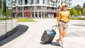 Mujer caminando con maleta después de elegir outfits de primavera para viaje.