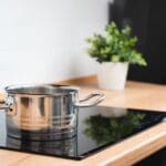 Placa de inducción moderna funcionando en una cocina contemporánea con utensilios compatibles.