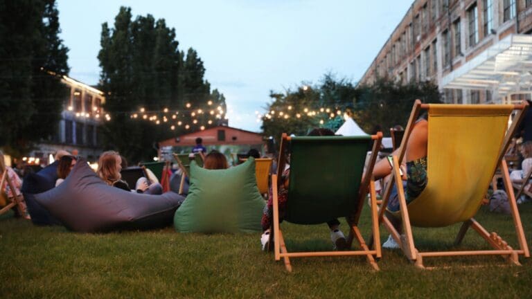 Personas disfrutando de un cine fórum al aire libre durante la proyección de una película con pantalla de cine profesional y ambiente comunitario.