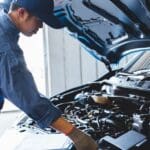 Mecánico realizando mantenimiento preventivo en coche con revisión periódica, cambio de aceite y revisión de filtros de aire.