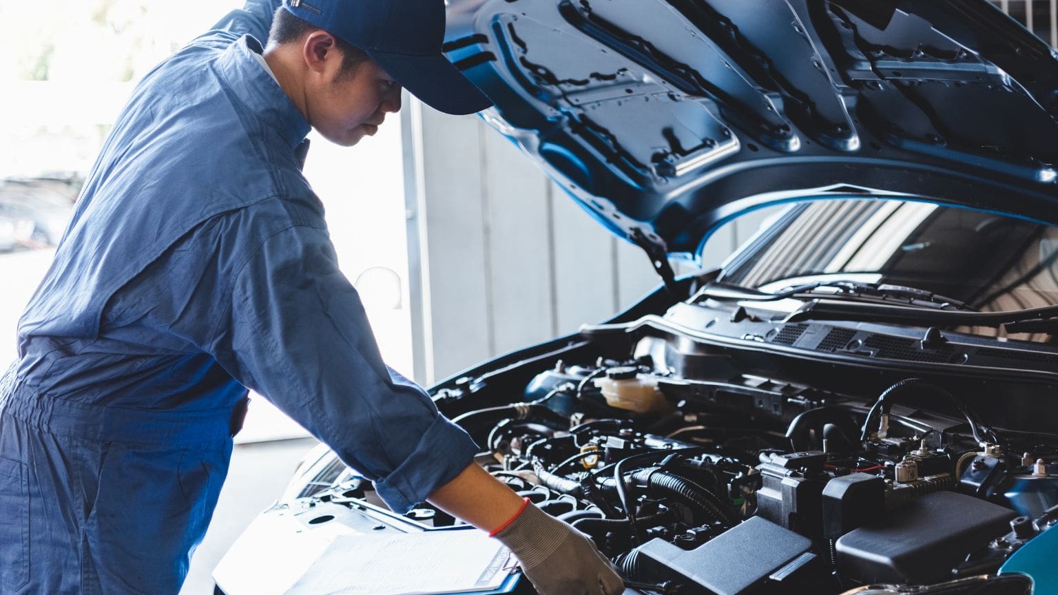 Mecánico realizando mantenimiento preventivo en coche con revisión periódica, cambio de aceite y revisión de filtros de aire.
