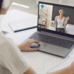 Estudiante sonriente aprendiendo inglés online con portátil desde casa
