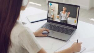 Estudiante sonriente aprendiendo inglés online con portátil desde casa