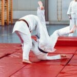 Grupo de personas entrenando artes marciales en un gimnasio, incluyendo mujeres, niños y adultos practicando técnicas de defensa personal y kickboxing en Reus
