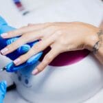 Técnica de manicura rusa aplicada en salón de belleza profesional en Madrid con acabado impecable.