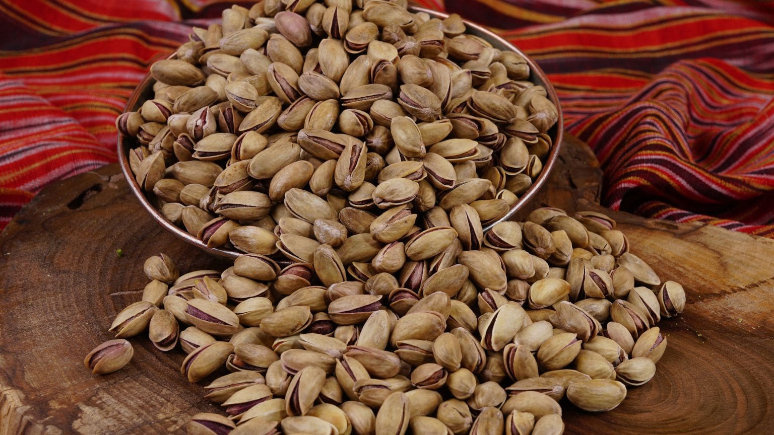 Pistachos crudos y tostados ecológicos presentados en cuencos de madera, ideales para una dieta saludable y sostenible