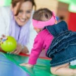 Niña pequeña realizando actividades de estimulación temprana con apoyo terapéutico.