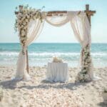 Playa de Ibiza o Formentera decorada para ceremonia LGTBIQ+ oficiada por maestra de ceremonias.