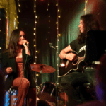 Dúo de música en vivo actuando en eventos en Barcelona, rodeados de público disfrutando de la experiencia cultural.