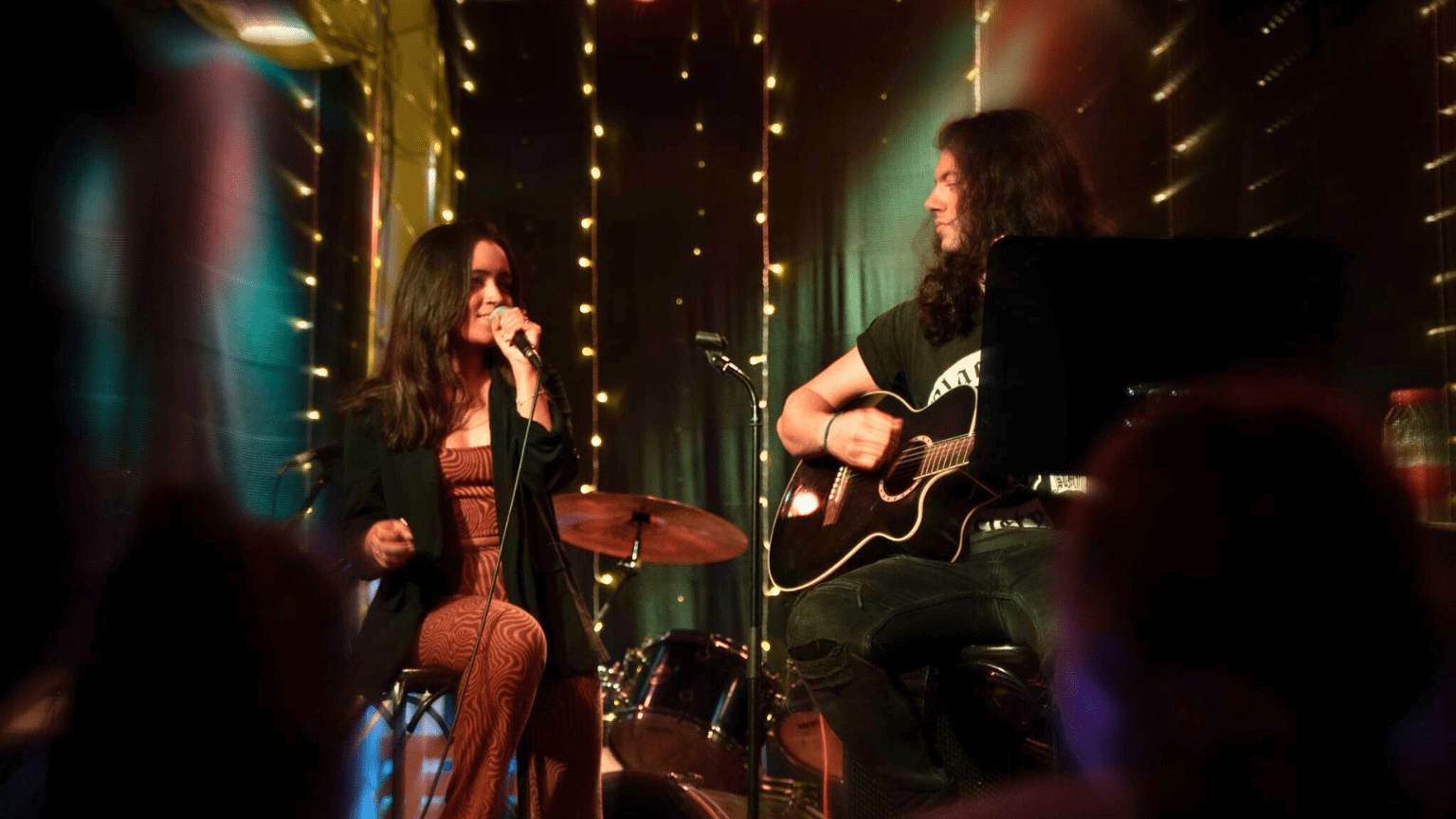 Dúo de música en vivo actuando en eventos en Barcelona, rodeados de público disfrutando de la experiencia cultural.