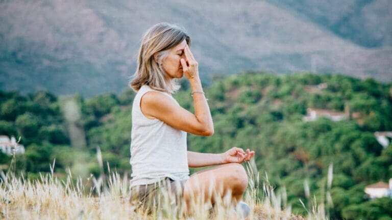 Mujer practicando breathwork al aire libre en entorno natural durante un retiro espiritual, simbolizando conexión, respiración consciente y bienestar holístico.