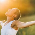 Mujer en conexión espiritual rodeada de naturaleza, expresando calma y empoderamiento interior.